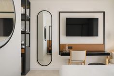 a bedroom with a bed, mirror and television mounted on the wall in it's corner