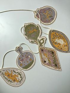 several ornaments are hanging on a white surface with strings attached to them and decorated with images of animals