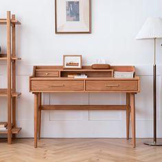 a wooden desk sitting next to a lamp on top of a hard wood floor