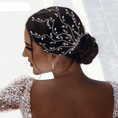 a woman in a wedding dress wearing a headpiece with pearls and leaves on it