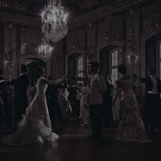 a man and woman dancing in a ballroom with chandelier hanging from the ceiling