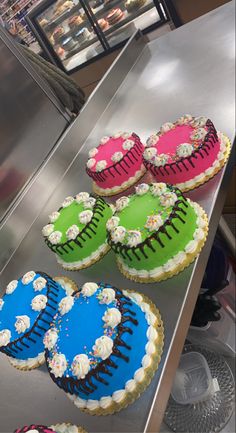 several decorated cakes sitting on top of a metal counter