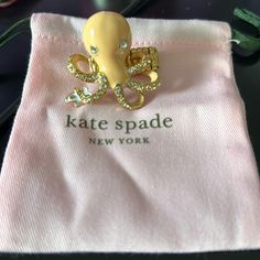 an octopus brooch sitting on top of a pink cloth covered in gold and diamonds