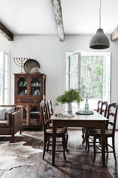 a dining room table and chairs in front of a window with an open bookcase