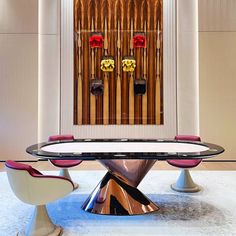 a glass table with two chairs in front of it and an organ on the wall behind it