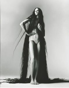 a woman with long hair standing in front of a white background