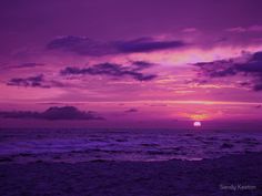 the sun is setting over the ocean with purple clouds