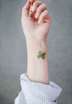 a small four leaf clover tattoo on the wrist