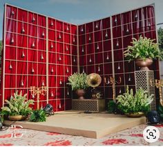 a stage set up with red curtains and potted plants