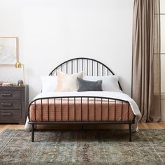 a bed sitting on top of a wooden floor next to a window