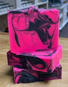 three soap bars are stacked on top of each other, one is pink and the other is black