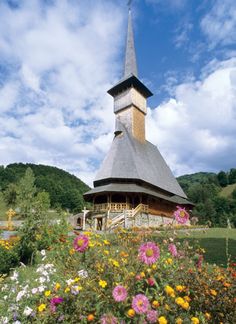 a building with a steeple surrounded by flowers