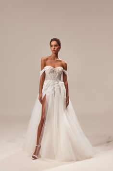 a woman in a white wedding dress with an off the shoulder slit and high slit