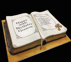 an open book cake with the words happy 90th birthday granny on it and a cross