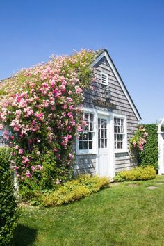 a house with pink flowers growing on it's side