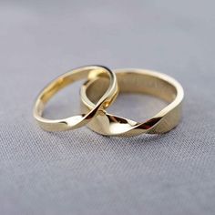 two wedding rings sitting on top of each other in front of a gray background,