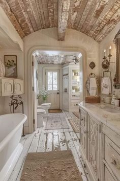 an old fashioned bathroom with white fixtures and wood ceilinging, along with a large bathtub