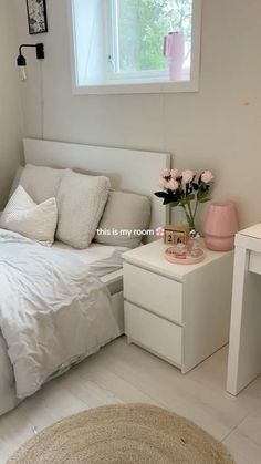 a bedroom with white furniture and pink flowers on the nightstands in front of the bed