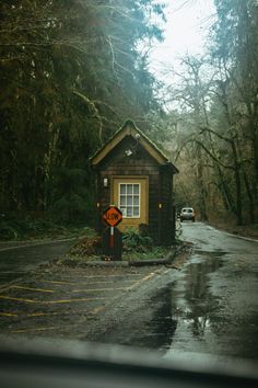 there is a small cabin in the middle of the road with a stop sign on it