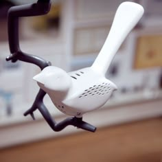 a white and black toy bird on a stick with it's legs spread out