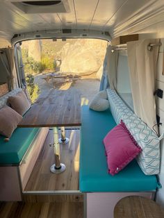 the inside of a camper with wood flooring and blue cushions on it's side