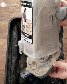 a person is holding a plastic container with sand in it and cleaning the bottom part