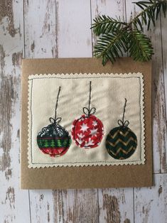 an ornament card with three ornaments hanging from it's side on a wooden surface