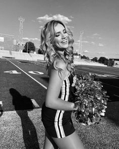 a beautiful young woman in a bathing suit holding a bouquet of flowers while standing on a field