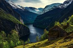 the mountains are covered in snow and green grass, with a body of water between them