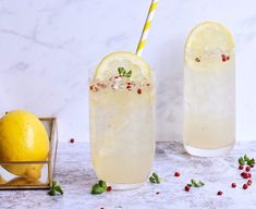 two glasses filled with lemonade and garnish next to an empty box full of lemons