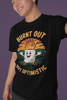 Elevate your camping wardrobe with our "Burnt Out but Optimistic" T-shirt! Featuring a whimsical marshmallow with a playful grin, flames flickering atop its head, this tee perfectly captures the spirit of adventure and resilience in the great outdoors. Made from soft, breathable fabric, it's perfect for those cozy campfire nights or hikes under the stars. Show off your love for camping and a good laugh, reminding everyone to stay cheerful, even when life gets a little toasty! Grab yours and let the good vibes roll! Product features - Shoulder tape for stability and comfort - No side seams for a sleek appearance - Ribbed collar retains shape and elasticity - Made from durable, smooth fabric - Ethically sourced 100% US cotton Care instructions - Machine wash: warm (max 40C or 105F) - Non-chl Funny Letter Print T-shirt For Outdoor, Custom Print Short Sleeve T-shirt For Outdoor, Cotton T-shirt With Funny Print For Outdoor Activities, Funny Print T-shirt For Outdoor Activities, Funny Text Short Sleeve T-shirt For Outdoor, Black Hiking T-shirt With Letter Print, Black Crew Neck T-shirt For Camping, Black Letter Print T-shirt For Hiking, Black T-shirt For Hiking With Letter Print