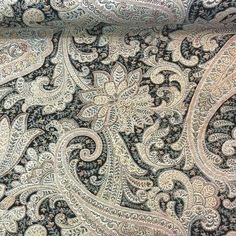 an intricate paisley print fabric with black and white accents on it's side,