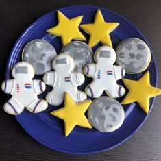 cookies decorated to look like astronauts and stars on a blue plate