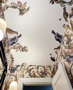 the ceiling is painted with birds and flowers on it, while an open door leads to another room