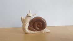 a snail figurine sitting on top of a wooden table