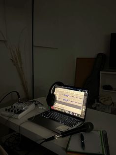 an open laptop computer sitting on top of a desk next to headphones and a calculator