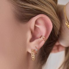 a close up of a person wearing gold ear rings and earrings with chains on them