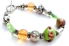 Fashion Jewellery - This is a bracelet with a green wedding cake bead, green and amber glass beads, and silver flowers, frog and spacers. It is 8" long, beads vary from 4mm to 17mm in width. Green Wedding Cake, Silver Bead Bracelet, Bead Bracelets, Silver Bead, Green Wedding, Amber Glass, Silver Flowers, Silver Beads, Pandora Charm Bracelet