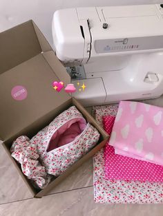 a sewing machine sitting next to a box with clothes in it and a pink bow tie