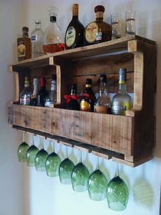 a wooden shelf with bottles and glasses hanging from it's sides on the wall