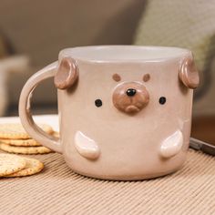 a mug with a bear face on it next to crackers