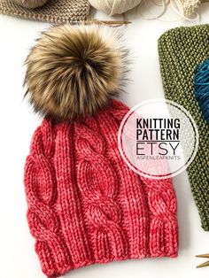 a knitted hat with a pom - pom sitting next to it