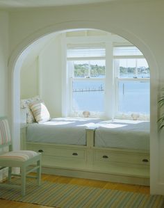 an arched window in a bedroom with two twin beds and a striped rug on the floor