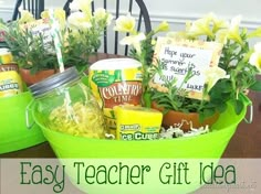 a green bucket filled with food and flowers on top of a table next to a sign that says, easy teacher gift idea