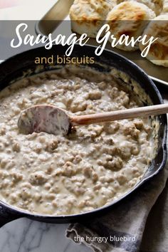 sausage gravy and biscuits in a cast iron skillet with a wooden spoon