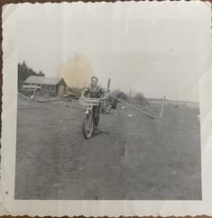 an old black and white photo of a person on a motorbike in a field