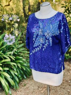 This is a vibrant blue floral sequin top blouse that is perfect with Jeans or a dressed up pant. The fabric is pure silk with sequin embellishment. This lovely top is made in India by Jasmine by K.V.M. Calif.  Measurements laying flat across: Pit to pit-22" Waist- 20" Length- 22.5" Sleeves- 13" Blue Sequin Fabric For Summer Night Out, Contrast Sequin Top For Evening In Spring, Sequin Tops For Evening In Spring, Festive Embellished Blue Blouse, Festive Blue Embellished Blouse, Blue Contrast Sequin Fabric For Spring, Blue Sequin Fabric With Contrast Sequin For Spring, Blue Sequin Fabric With Contrast Design For Spring, Spring Embellished Silk Tops