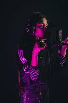 a woman with headphones on holding a hair comb and looking at the camera while standing in front of a black background