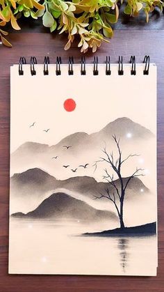 a spiral notebook with an image of a tree and birds flying over the mountain range