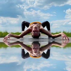 a man laying on the ground in front of a body of water with his reflection